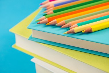 Kitap yığını üzerinde renkli kalemler