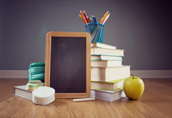 Chalkboard, apple and colorful stationery. — Stock Photo, Image