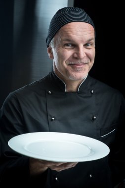 siyah bir tabak gösterilen üniforma şef