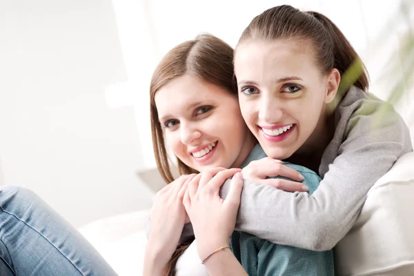 Girlfriends hugging on sofa — Stock Photo, Image