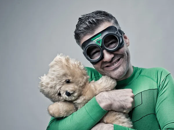 Lächelnder Superheld kuschelt einen Teddybär — Stockfoto