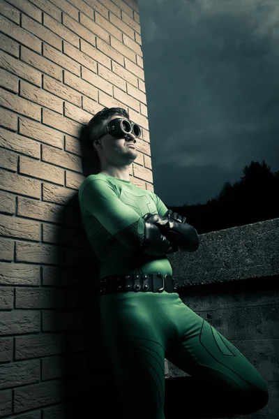 Cool superhero leaning to a brick wall — Stock Photo, Image