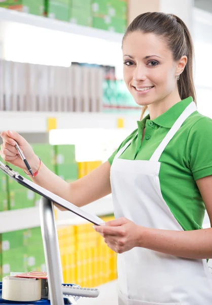 Female sales clerk holding clipboard — Stock Photo, Image