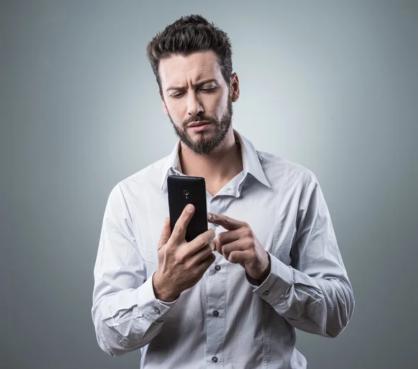 Disappointed man typing with his smartphone — Stock Photo, Image