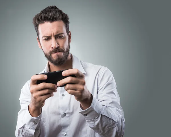 Bonito homem jogando com smartphone — Fotografia de Stock