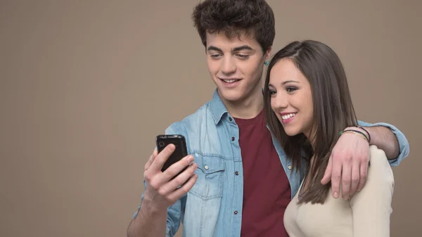 Usmívající se pár s mobilním telefonem — Stock fotografie