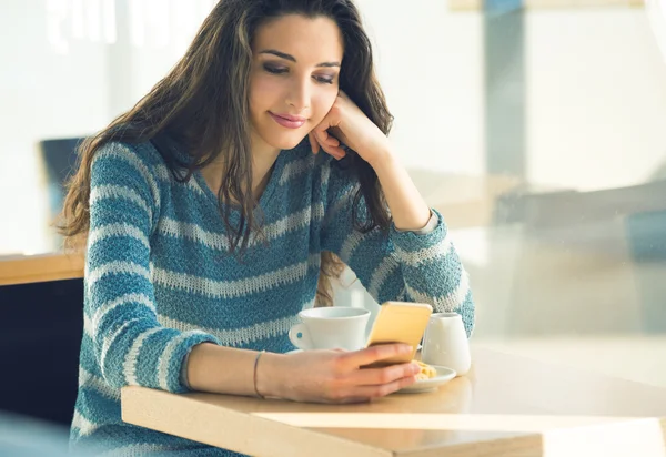 Mujer joven en la cafetería con teléfono inteligente — Foto de Stock