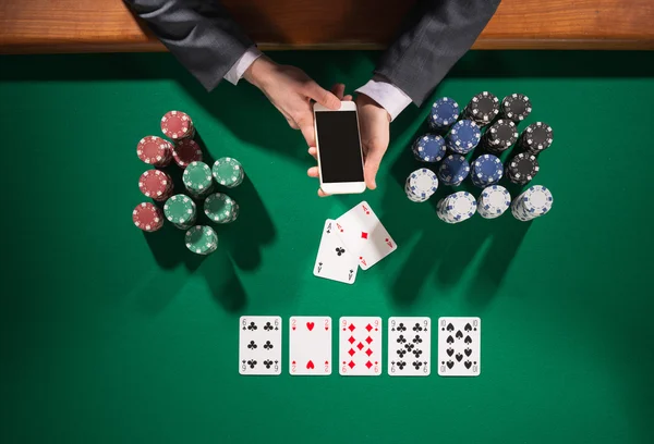 Αρσενικό πόκερ παίκτη χρησιμοποιώντας ένα smartphone — Φωτογραφία Αρχείου