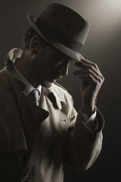 Detective adjusting his hat — Stock fotografie