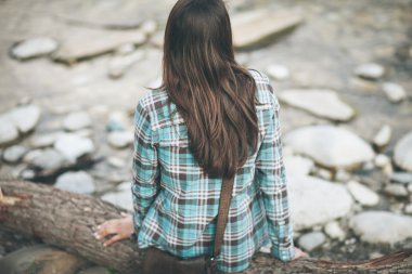 Genç bir kadın nehir kenarında oturuyor.