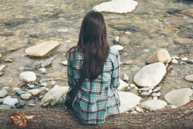 Genç bir kadın nehir kenarında oturuyor.