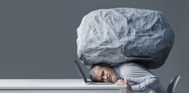 Bir iş adamı dizüstü bilgisayarında omuzlarında büyük bir kaya parçasıyla çalışır. Stres, vergi baskısı, anksiyete ve modern yaşamın zihinsel yükünü simgeler..