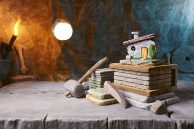 Model ev ve taş tabletlerle antik tarih öncesi emlakçı masası: Taş Devri konseptinde gayrimenkul