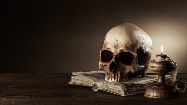 kafatası, mum ve açık antik kitap