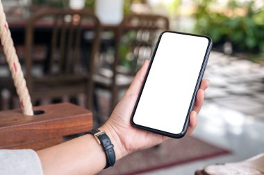 Siyah cep telefonuyla beyaz ekranı olan bir kadının el resmi.