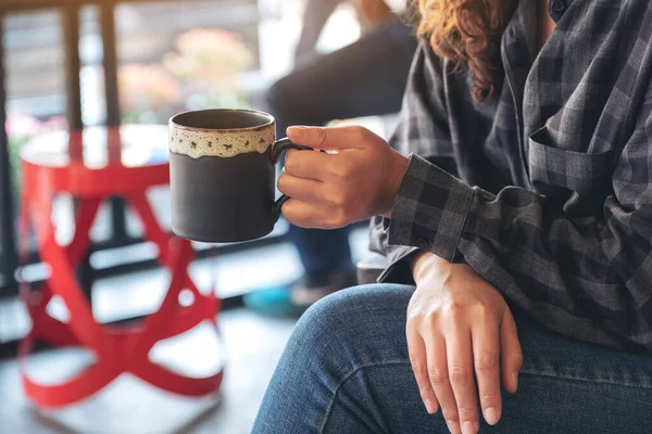一个女人坐在咖啡店里喝热咖啡的照片 — 图库照片