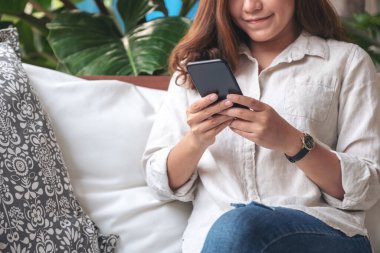 Kafedeki akıllı telefonu tutan, kullanan ve ona bakan güzel bir kadının yakın plan görüntüsü.