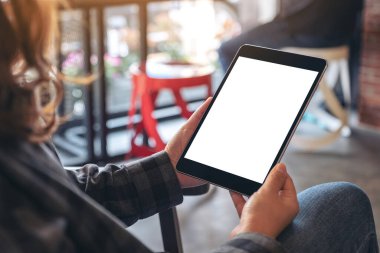 Kafede elinde siyah tabletle boş ekranı olan bir kadının görüntüsü.