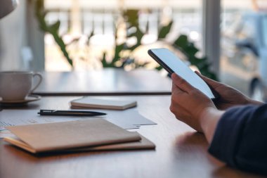 Ofiste çalışırken cep telefonu tutan ve kullanan bir kadının yakın plan resmi