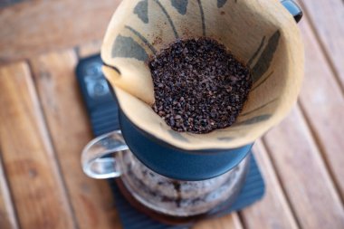 Kahve telvesinin dijital kahve ölçeğindeki kağıt filtredeki yakın görüntüsü, aynı zamanda eski ahşap masa üzerinde damlayan bir kahve yapıyor.