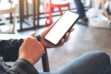 Kafedeki boş beyaz masaüstü ekranlı siyah cep telefonlu bir kadının el resmi.