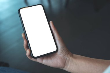 Boş masaüstü ekran ile siyah cep telefonu tutan bir kadının el görüntüsü 