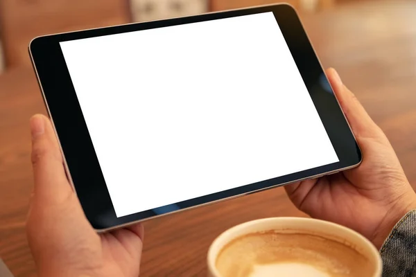 tablet pc with blank white screen horizontally with coffee cup on wooden table