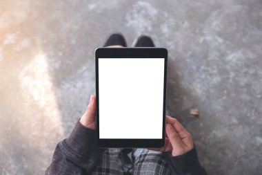 Üst görünümde, yerde otururken beyaz masaüstü ekranlı ve siyah tablet tableti kullanan kadınların ellerinin görüntüsü var 