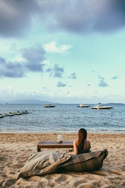 Güzel bir Asyalı kadın sahilde oturmaktan zevk alır.
