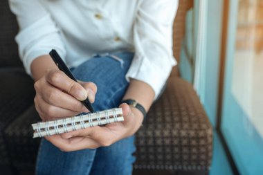 Boş bir deftere bir kadının ellerini tutarken ve yazarken yakın plan görüntüsü. 