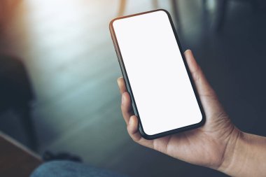 Boş masaüstü ekran ile siyah cep telefonu tutan bir kadının el görüntüsü 