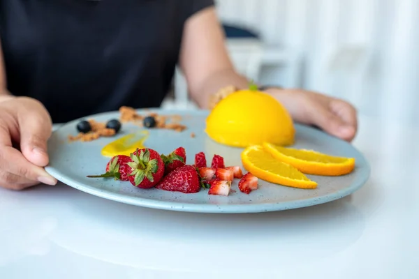 Eine Frau Hält Café Einen Teller Orangenkuchen Mit Gemischten Früchten — Stockfoto