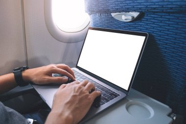 Boş beyaz masaüstü ekran ile dizüstü bilgisayarı kullanan ve yazan bir adamın kabinde otururken görüntüsü
