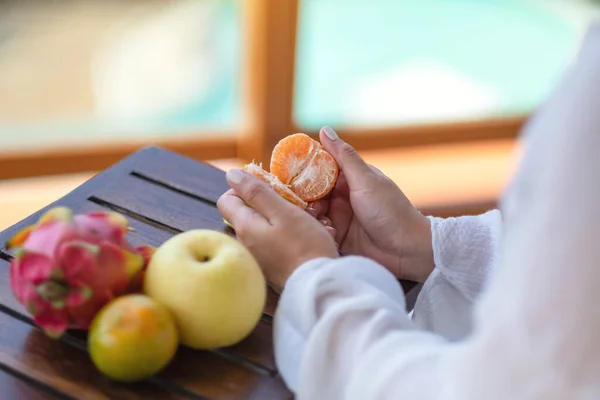 Eine Frau Hält Und Schält Eine Orange Zum Essen Mit — Stockfoto