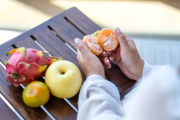 Eine Frau Hält Und Schält Eine Orange Zum Essen Mit — Stockfoto