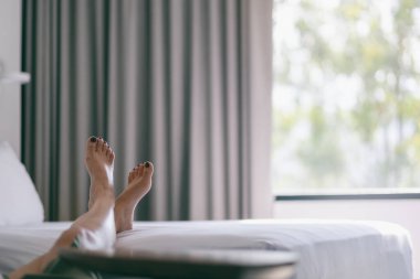 Beyaz bir yatakta bir kadının ayaklarının yakın plan görüntüsü.