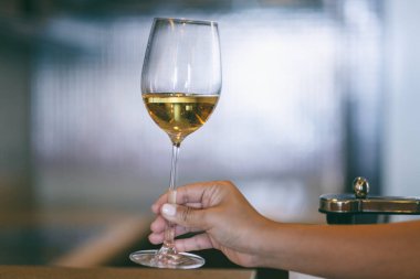 Arka planda bulanık şarap kadehi tutan bir kadının yakın plan görüntüsü.