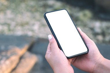 Plaj ve deniz kenarındaki boş masaüstü ekranlı, elinde siyah cep telefonu olan bir kadının görüntüsü. 