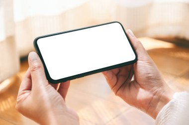 Boş masaüstü ekranı olan siyah cep telefonunu yatay olarak tutan ve kullanan elleri görüntüle 