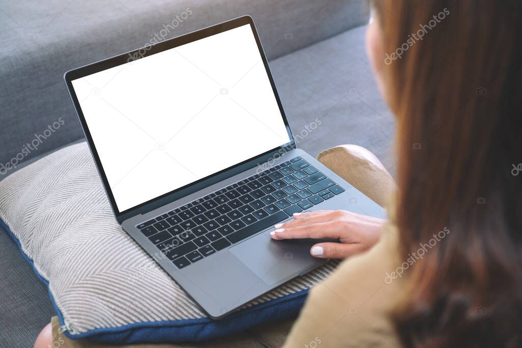 Mockup image of a woman using and touching on laptop touchpad with blank white screen while sitting in living room