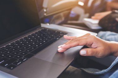 Kulübede otururken dizüstü bilgisayarın dokunmatik dokunuşunu kullanan bir kadının yakın plan görüntüsü.