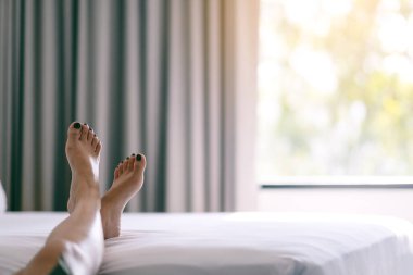 Beyaz bir yatakta bir kadının ayaklarının yakın plan görüntüsü.