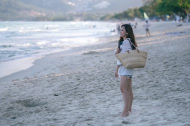 Bir kadın kumsalda geziniyor ve güzel bir deniz manzarasına bakıyor.