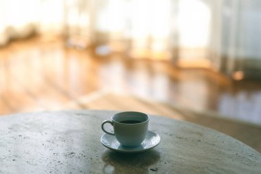 Evin perdesinin yanındaki masada beyaz bir fincan sıcak kahve.