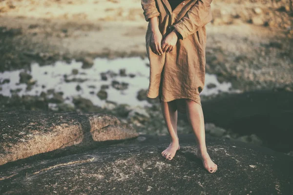 站在海滩边岩石上的女人的腿的塑像 — 图库照片