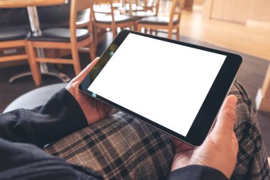 Kafede otururken elinde siyah tablet olan beyaz ekranlı bir kadının görüntüsü.