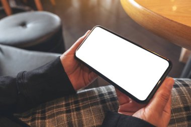 Boş beyaz ekranlı siyah cep telefonunu yatay olarak tutan ellerin görüntüsü 