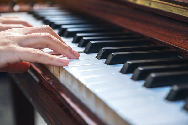 Closeup image of hands playing a vintage wooden grand piano