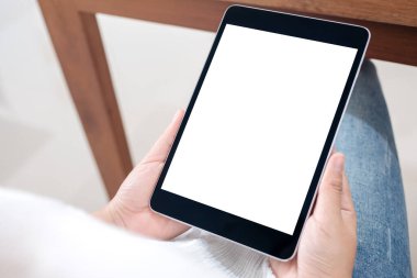 Kafede otururken elinde siyah tablet olan beyaz ekranlı bir kadının görüntüsü.