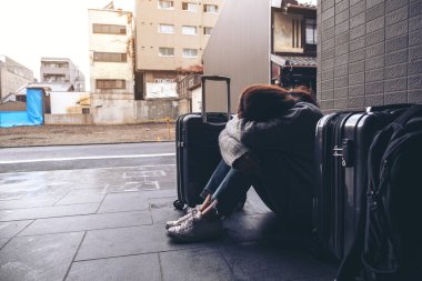 Yerde bir sürü bavulla seyahat ederken üzgün ve ağlayan bir kadın.